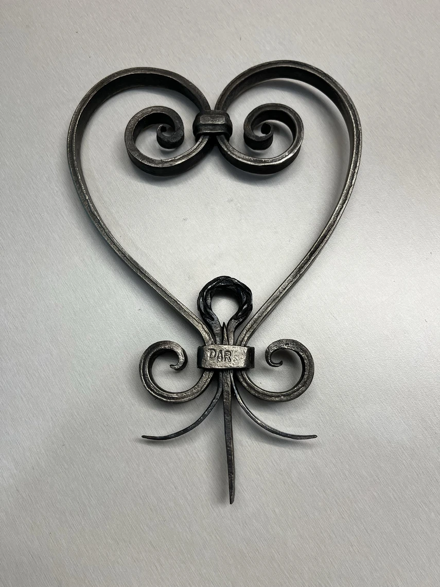 An image of a hand-forged metal symbol shaped like a heart.