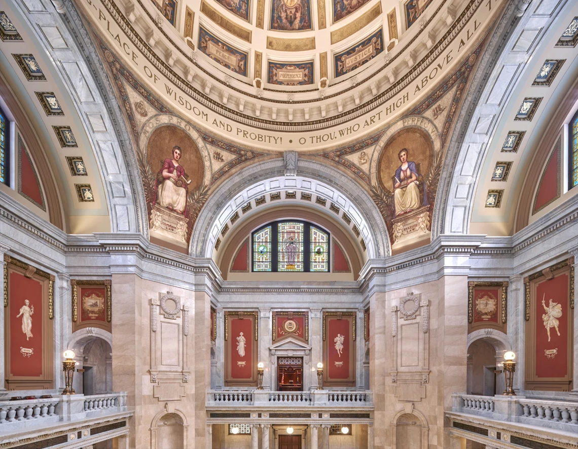This image shows the elaborately decorated interior of a building with a dome ceiling, arches, columns, and balustrades.