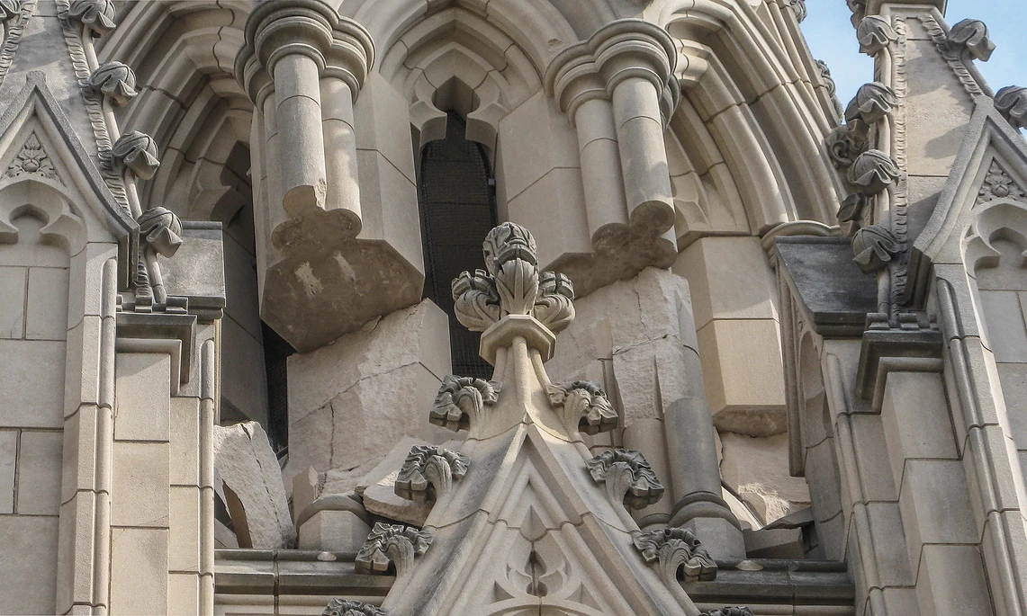 This image shows broken and severely rotated stones of a large, elaborately carved Gothic-style pinnacle on a cathedral that was damaged by an earthquake.