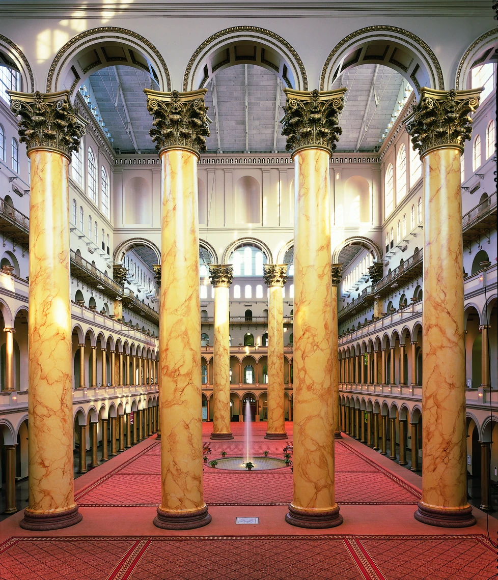 Five giant faux-marble columns topped with Corinthian capitals are seen filling the Great Hall of the National Building Museum.